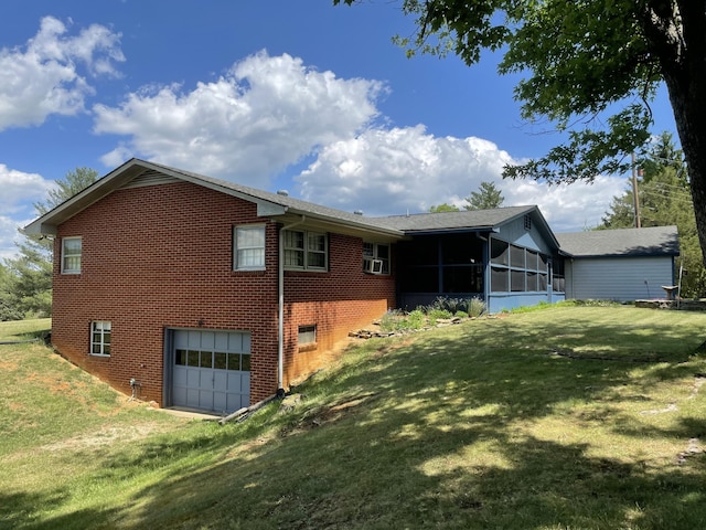 rear view of house featuring a sunroom, an attached garage, brick siding, and a lawn