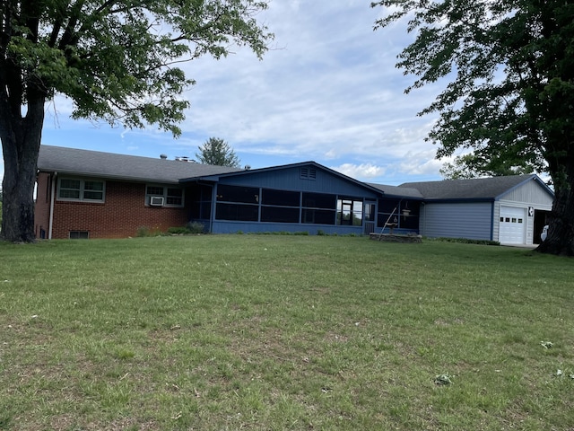 rear view of property featuring a sunroom, a garage, a lawn, brick siding, and cooling unit