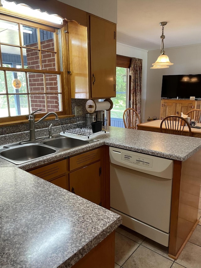 kitchen with dishwasher, a sink, a peninsula, light tile patterned floors, and decorative light fixtures