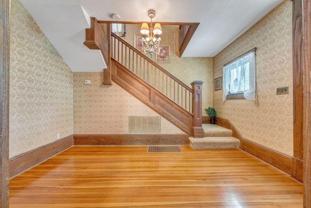 3759 Mill Iron Rd, Goodview, VA 24095 - unfurnished living room with hardwood / wood-style floors, stairway, wallpapered walls, and a chandelier