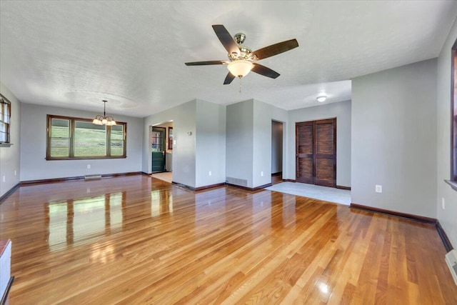 1104 Dolly Ann Dr, Covington, VA 24426 - unfurnished living room featuring a chandelier, baseboards, light wood finished floors, ceiling fan, and a textured ceiling