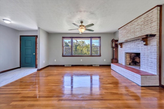 1104 Dolly Ann Dr, Covington, VA 24426 - unfurnished living room featuring wood finished floors, ceiling fan, a brick fireplace, a textured ceiling, and baseboards