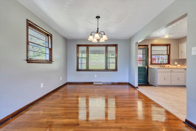 1104 Dolly Ann Dr, Covington, VA 24426 - unfurnished dining area featuring light wood-style flooring, a chandelier, baseboards, and a sink