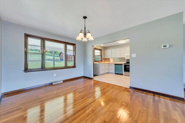 1104 Dolly Ann Dr, Covington, VA 24426 - unfurnished living room featuring a chandelier, light wood-style floors, baseboards, and plenty of natural light