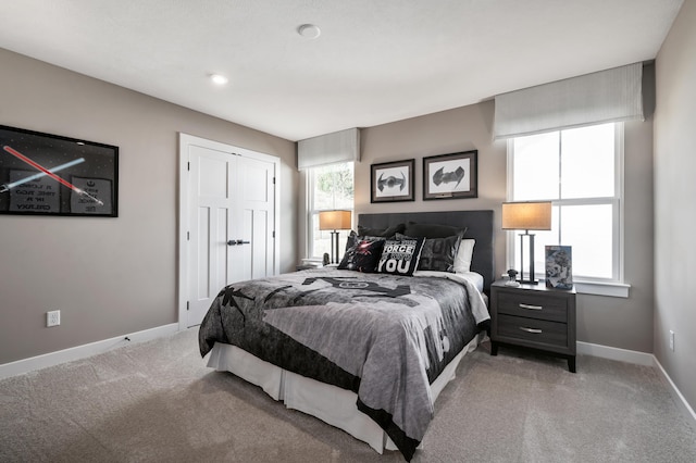 bedroom with light carpet, baseboards, and a closet