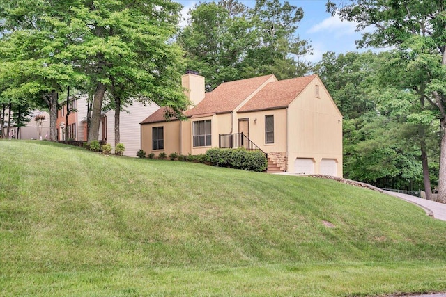 view of front facade with an attached garage, a chimney, a front lawn, and a shingled roof