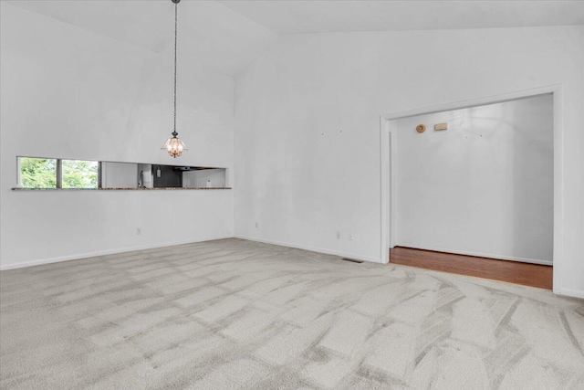 carpeted empty room featuring high vaulted ceiling and baseboards