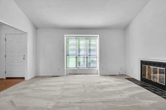 unfurnished living room featuring a fireplace with flush hearth, carpet, and baseboards