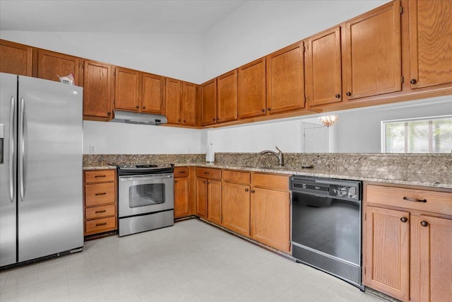 kitchen featuring appliances with stainless steel finishes, under cabinet range hood, light stone countertops, vaulted ceiling, and a sink