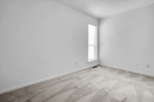 spare room featuring carpet and baseboards