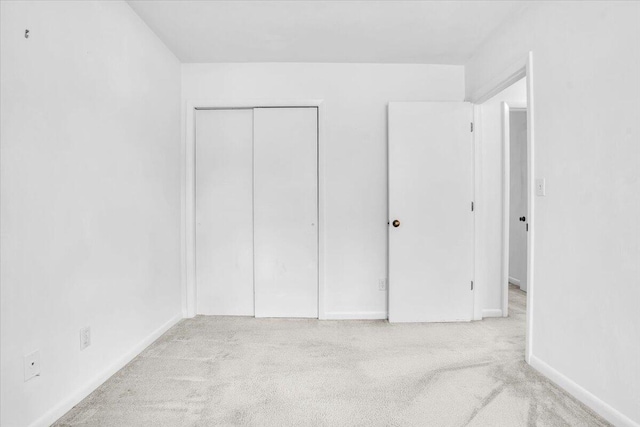 unfurnished bedroom with carpet floors, a closet, and baseboards