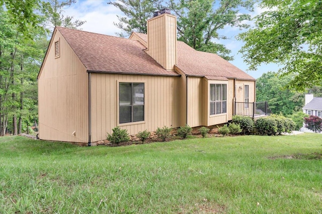 view of front of house featuring a chimney, a shingled roof, and a front lawn