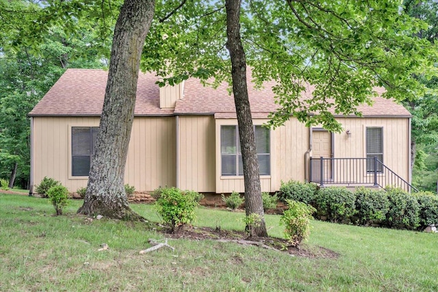 view of front of home with a shingled roof and a front yard