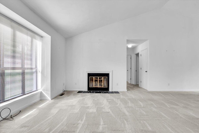 unfurnished living room with vaulted ceiling, carpet flooring, a fireplace with flush hearth, and baseboards