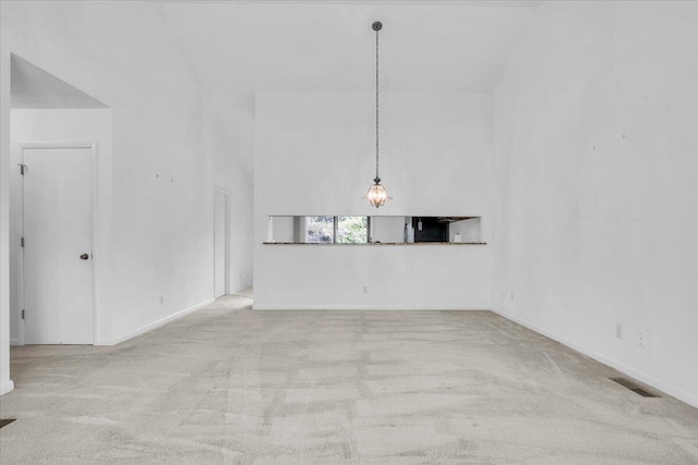 unfurnished room featuring carpet floors, baseboards, and a towering ceiling