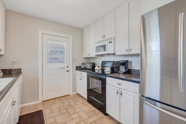 kitchen with freestanding refrigerator, black range with electric cooktop, white microwave, dark countertops, and white cabinetry