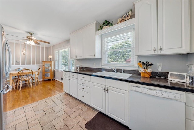 kitchen with dishwasher, a sink, freestanding refrigerator, dark countertops, and ceiling fan
