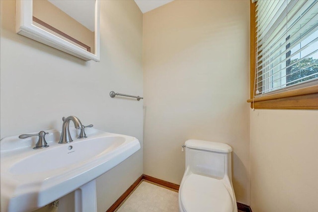 half bathroom featuring a sink, toilet, and baseboards
