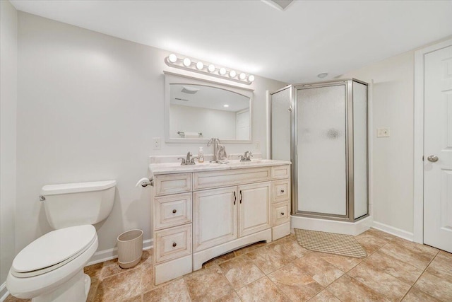 bathroom featuring a stall shower, toilet, double vanity, and baseboards