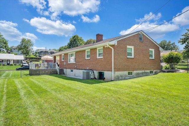 rear view of house with a chimney, brick siding, a wooden deck, and central air condition unit