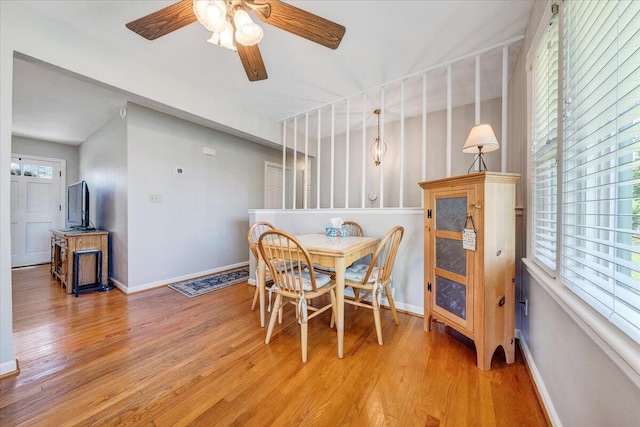 dining space with light wood-style flooring, a ceiling fan, and baseboards