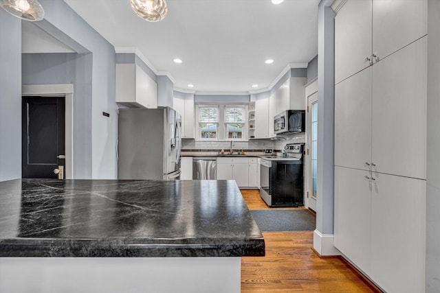 2102 Berkley Ave SW, Roanoke, VA 24015 - kitchen featuring appliances with stainless steel finishes, light wood-style floors, dark countertops, white cabinets, and a sink