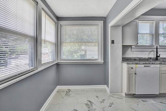 1228 Thomas Ave NW, Roanoke, VA 24017 - kitchen featuring dishwashing machine, light marble finish flooring, baseboards, a sink, and dark stone counters