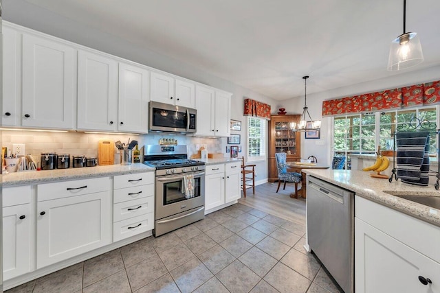 1017 Joffrey Dr, Huddleston, VA 24104 - kitchen with stainless steel appliances, backsplash, light tile patterned floors, white cabinetry, and baseboards