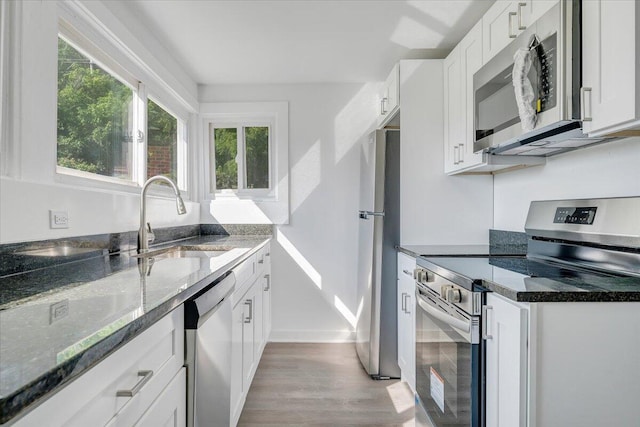 1008 Primrose St SE, Roanoke, VA 24014 - kitchen with stainless steel appliances, light wood-style floors, dark stone counters, and white cabinets