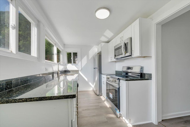 1008 Primrose St SE, Roanoke, VA 24014 - kitchen with stainless steel appliances, white cabinetry, light wood-style floors, and dark stone countertops
