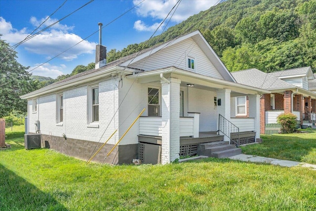 1008 Primrose St SE, Roanoke, VA 24014 - view of front of home with brick siding, a chimney, a front lawn, and a porch