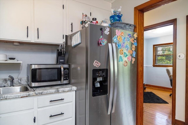 1829 Court St NW, Roanoke, VA 24012 - kitchen featuring stainless steel appliances, a sink, wood finished floors, light countertops, and white cabinetry