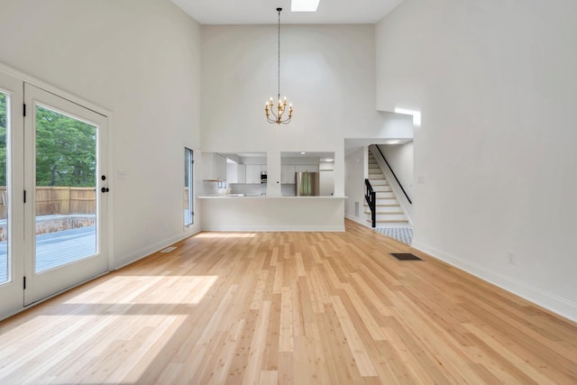 6695 Raintree Rd, Roanoke, VA 24018 - unfurnished living room with a chandelier, a towering ceiling, light wood-type flooring, baseboards, and stairway