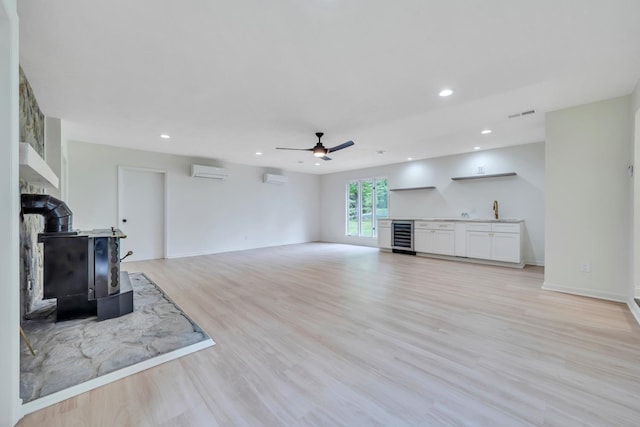 6695 Raintree Rd, Roanoke, VA 24018 - unfurnished living room with a wall mounted AC, ceiling fan, beverage cooler, light wood-type flooring, and a wood stove