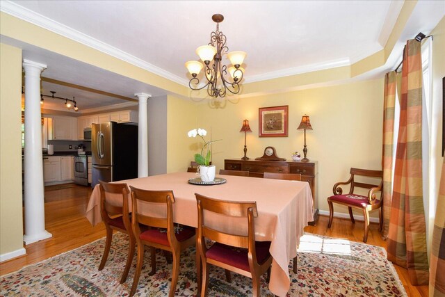 7635 Peebles Ln, Roanoke, VA 24018 - dining room featuring light wood-style flooring, crown molding, a chandelier, a tray ceiling, and decorative columns