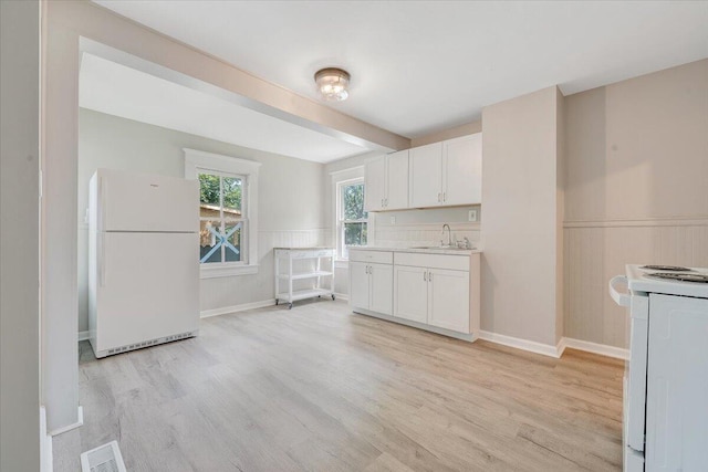 1120 6th St SE, Roanoke, VA 24013 - kitchen featuring white appliances, light wood-style flooring, white cabinets, light countertops, and wainscoting