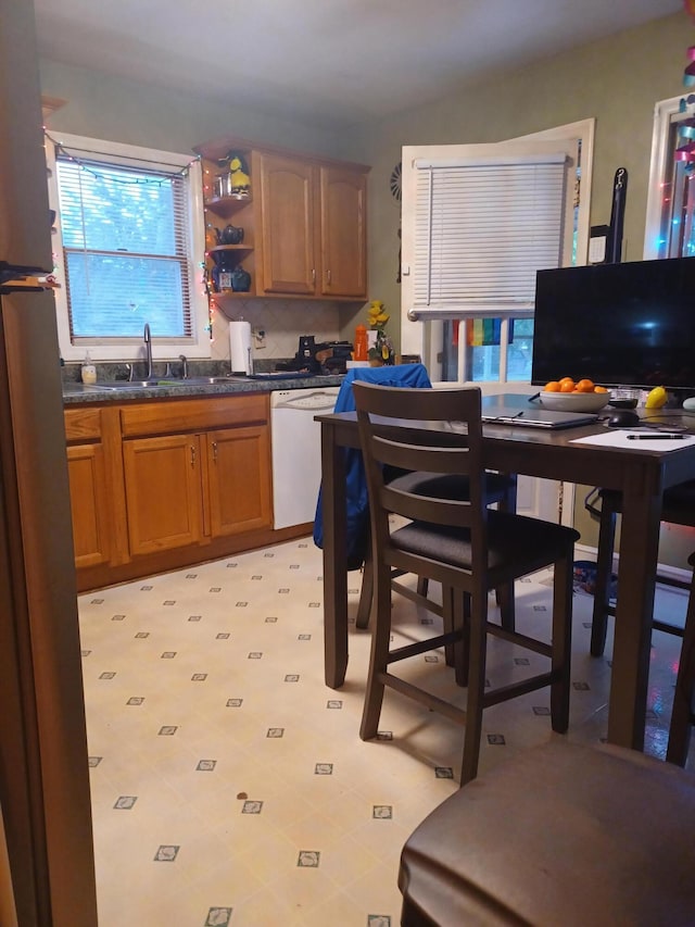 2521 Chatham St NW, Roanoke, VA 24012 - kitchen with a sink, dishwasher, brown cabinetry, dark countertops, and freestanding refrigerator