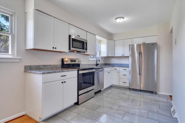 3734 Long Meadow Ave NW, Roanoke, VA 24017 - kitchen with stainless steel appliances, white cabinets, light stone countertops, baseboards, and light marble finish flooring