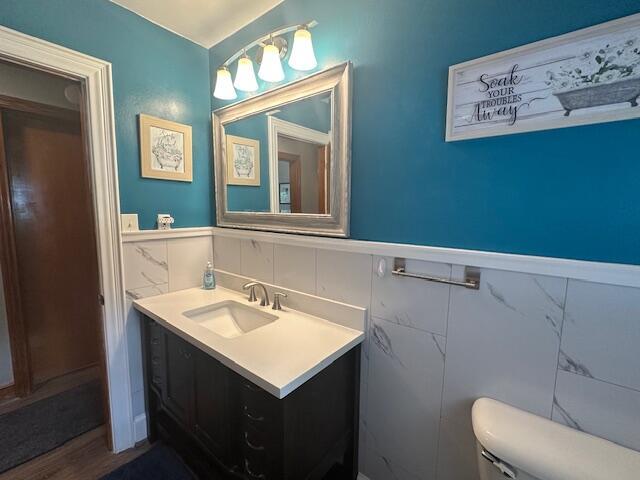 586 Graceland Dr, Bassett, VA 24055 - half bath with toilet, vanity, wainscoting, tile walls, and wood finished floors