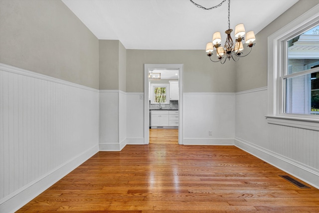 4816 Colonial Ave, Roanoke, VA 24018 - unfurnished dining area with a chandelier, light wood-style flooring, wainscoting, and a sink