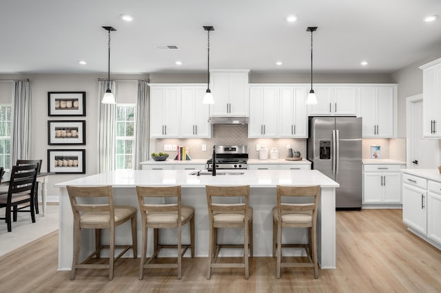 7272 Fairway Ridge Cir, Salem, VA 24153 - kitchen featuring stainless steel appliances, under cabinet range hood, a kitchen island with sink, decorative backsplash, and light wood finished floors
