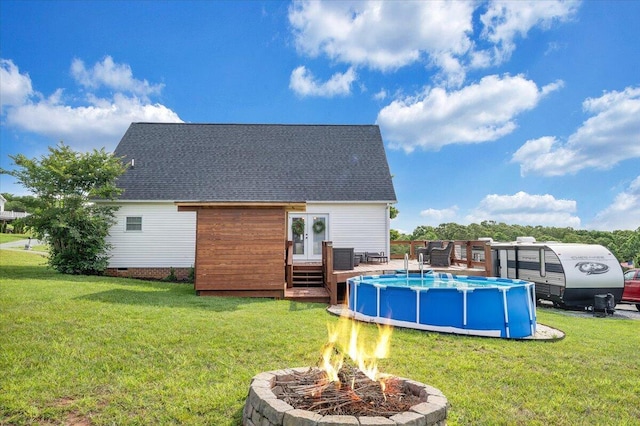 1028 Park Mountain Ter, Huddleston, VA 24104 - rear view of property featuring an outdoor fire pit, an outdoor pool, a wooden deck, roof with shingles, and a lawn