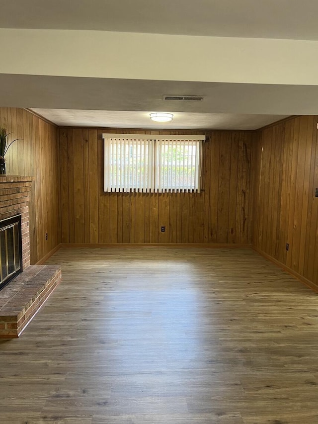 1878 Cranwell Dr, Vinton, VA 24179 - unfurnished living room with wood finished floors, wooden walls, a brick fireplace, and baseboards