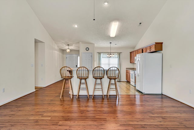 1801 Meadows Ct, Vinton, VA 24179 - kitchen with white appliances, a kitchen breakfast bar, wood finished floors, brown cabinetry, and a textured ceiling
