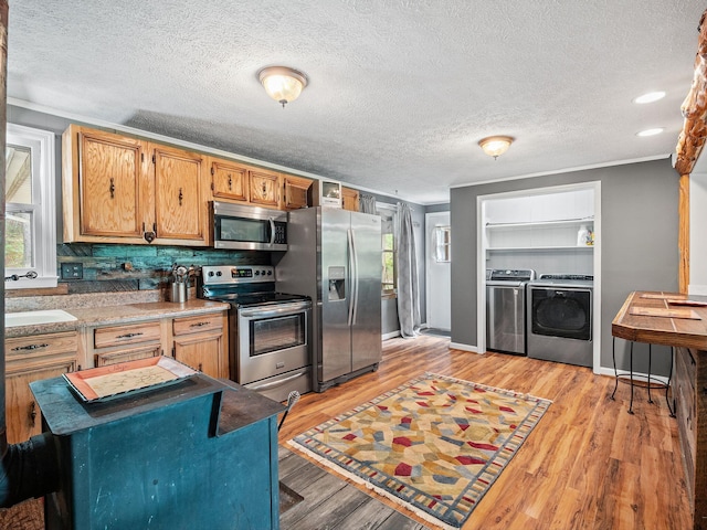 6357 Breckinridge Mill Rd, Fincastle, VA 24090 - kitchen featuring appliances with stainless steel finishes, washer and clothes dryer, healthy amount of natural light, light wood-style flooring, and a textured ceiling