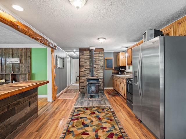 6357 Breckinridge Mill Rd, Fincastle, VA 24090 - kitchen with appliances with stainless steel finishes, baseboards, a textured ceiling, a wood stove, and light wood-style flooring