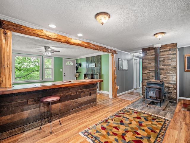 6357 Breckinridge Mill Rd, Fincastle, VA 24090 - bar area featuring ornamental molding, wood finished floors, a wood stove, baseboards, and a textured ceiling