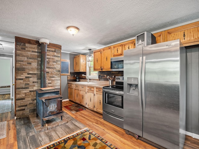 6357 Breckinridge Mill Rd, Fincastle, VA 24090 - kitchen with appliances with stainless steel finishes, a wood stove, a sink, light wood-style floors, and a textured ceiling