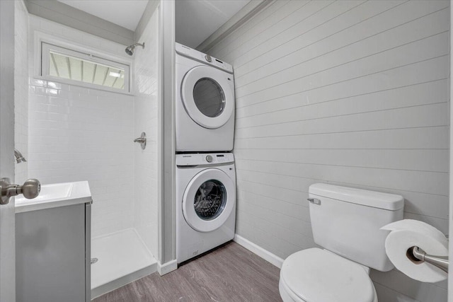 1006 10th St, Glasgow, VA 24555 - bathroom with stacked washing machine and dryer, a stall shower, wood finished floors, toilet, and baseboards