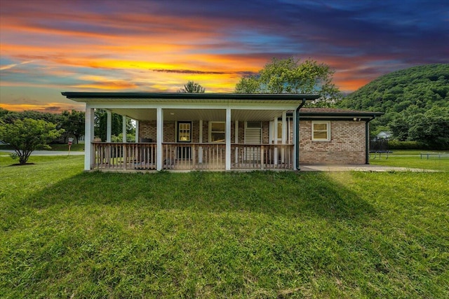 1006 10th St, Glasgow, VA 24555 - view of front facade with covered porch, a yard, and brick siding